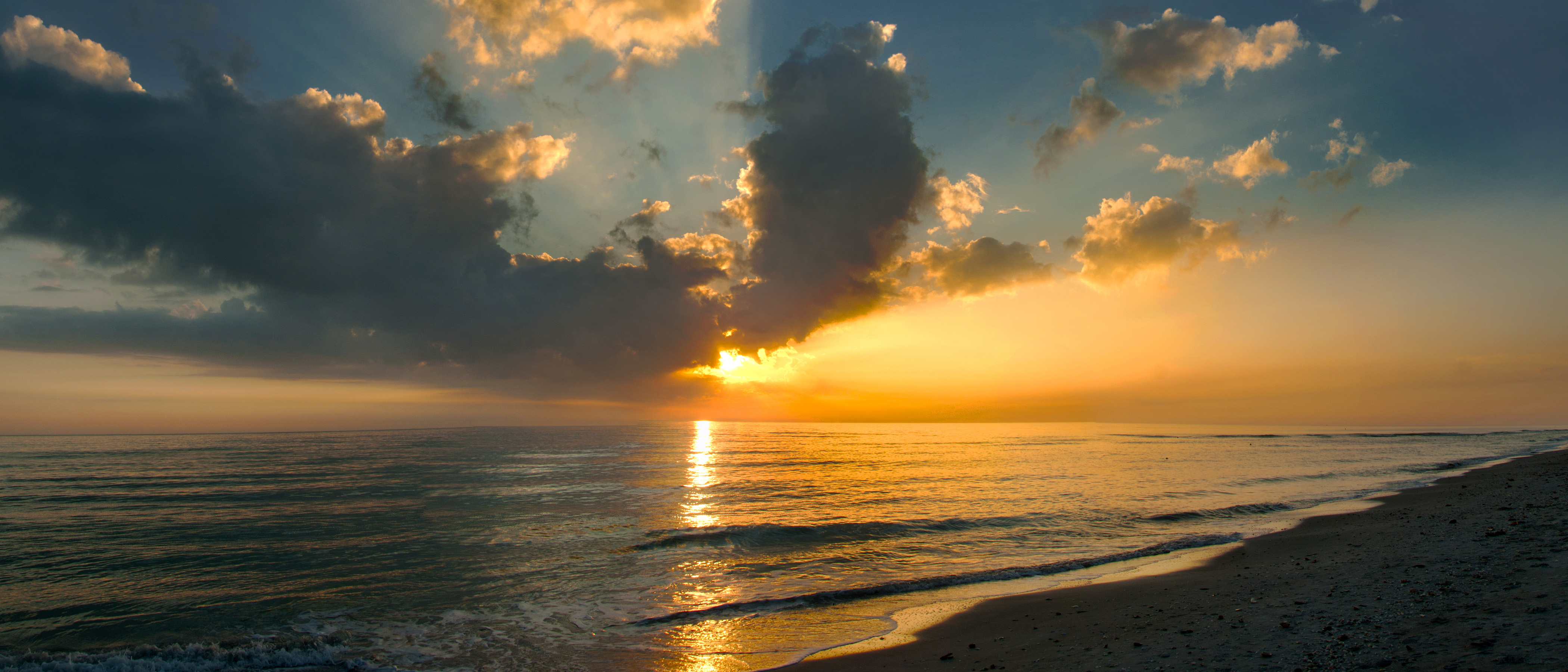 a serene sunset shines an orange and yellow light over the Atlantic Ocean